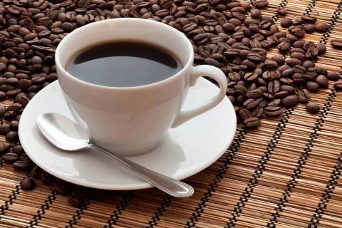 Cup of Coffee on a mat next to coffee beans