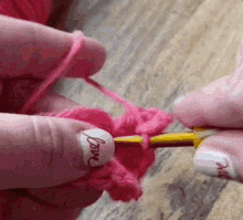 Person crocheting a pink heart